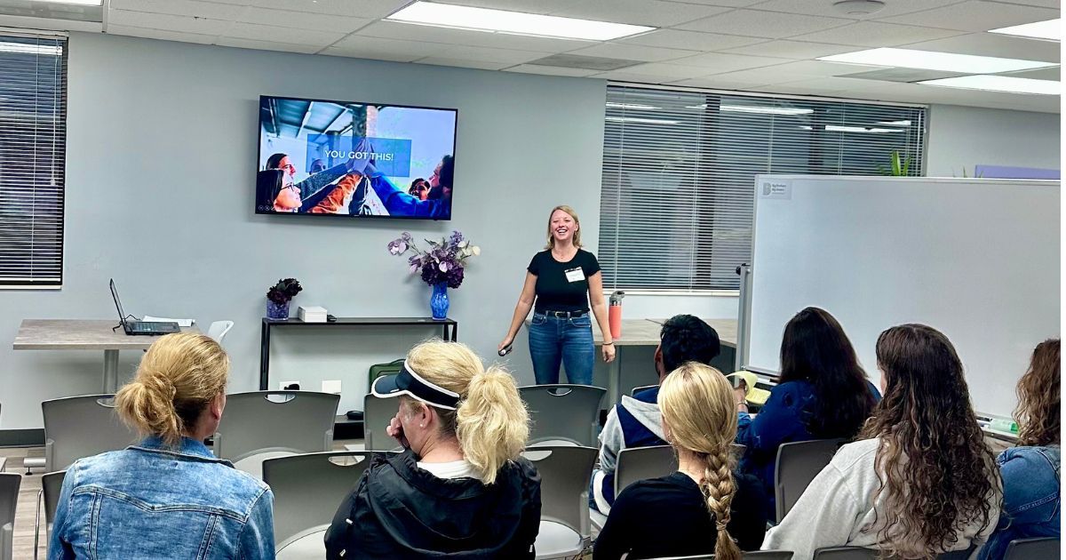 A tall blonde woman named Jackie speaking to students and parents about college planning. 