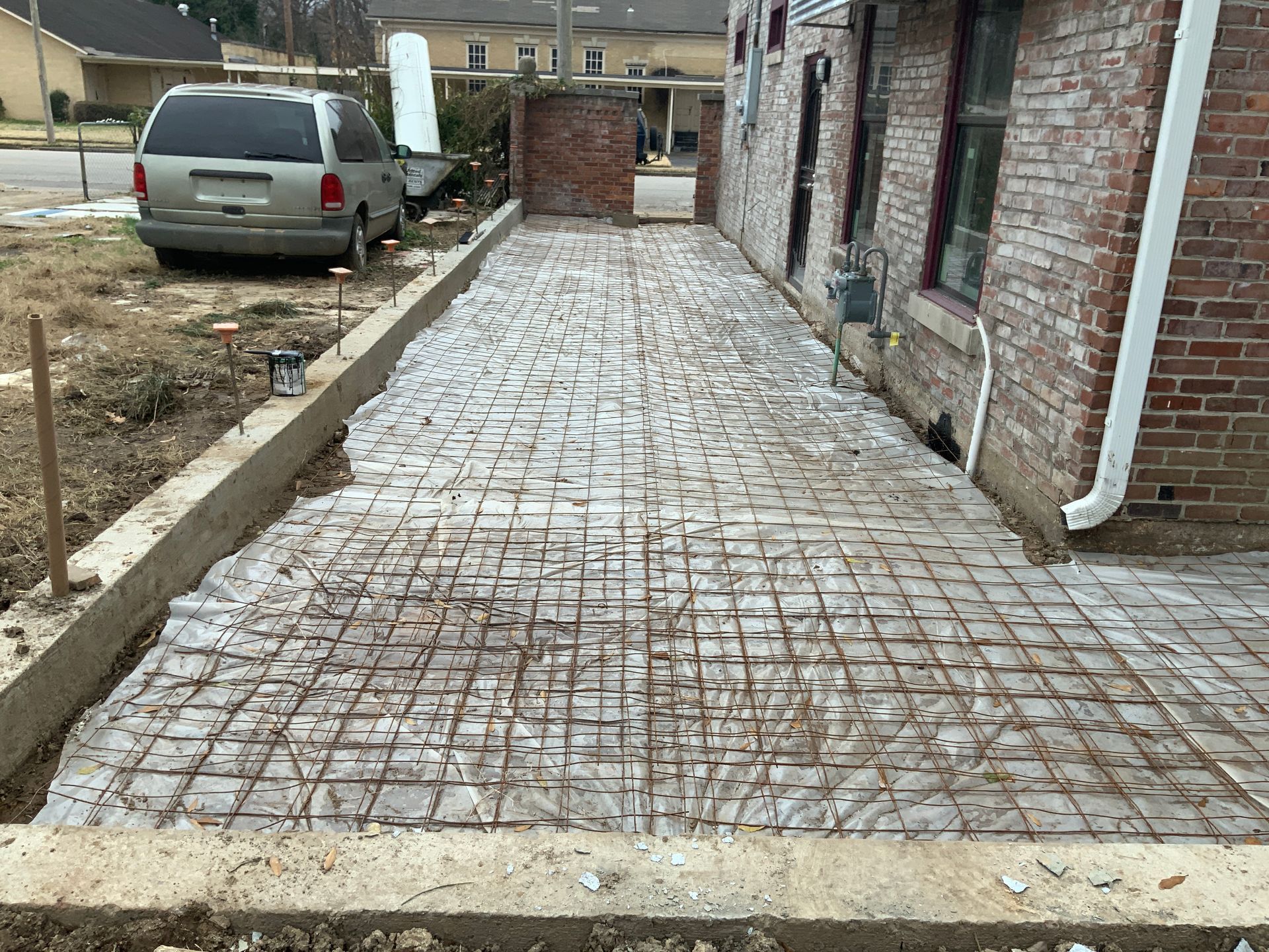 A van is parked in a driveway next to a brick building.