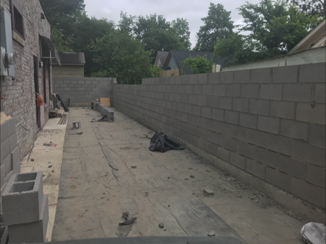 A brick wall is being built in the backyard of a house.