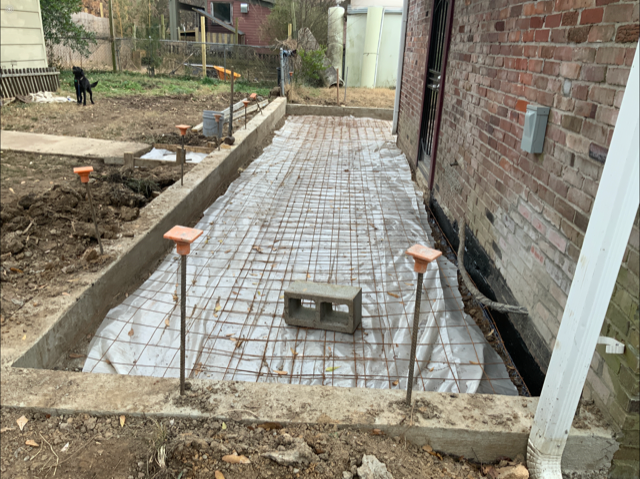 A concrete walkway is being built in front of a brick building.