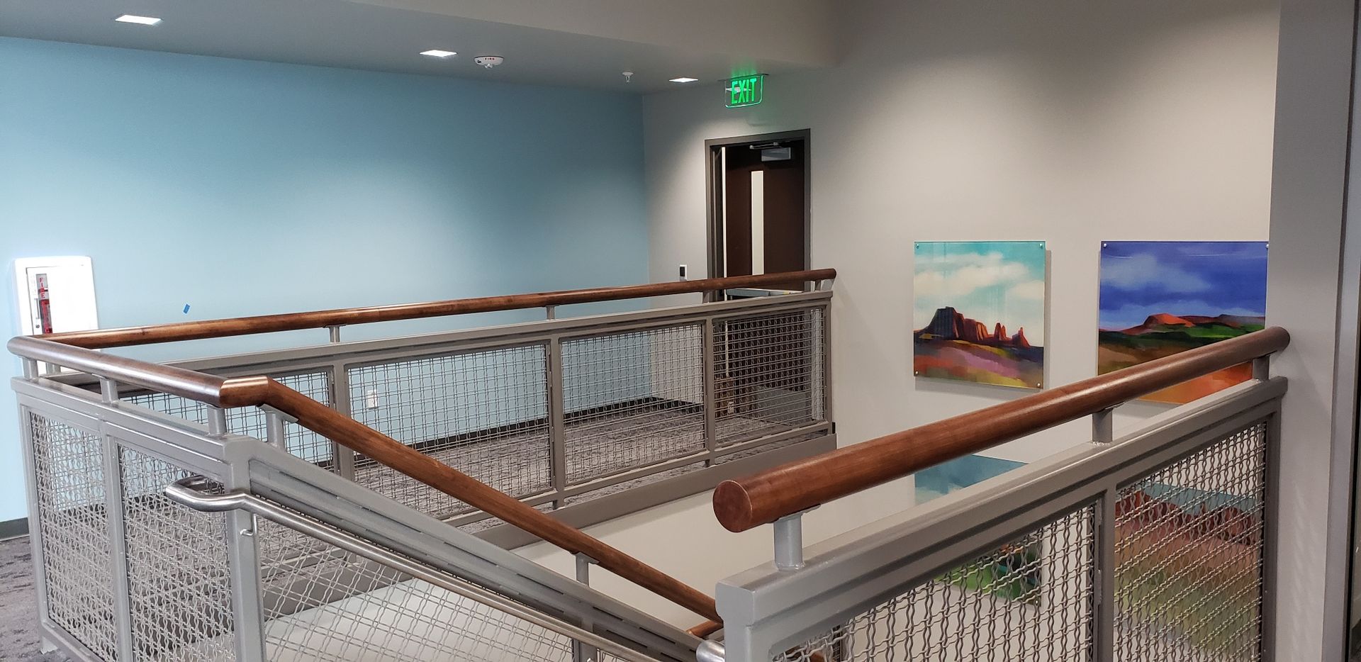 A staircase with a fence and paintings on the wall