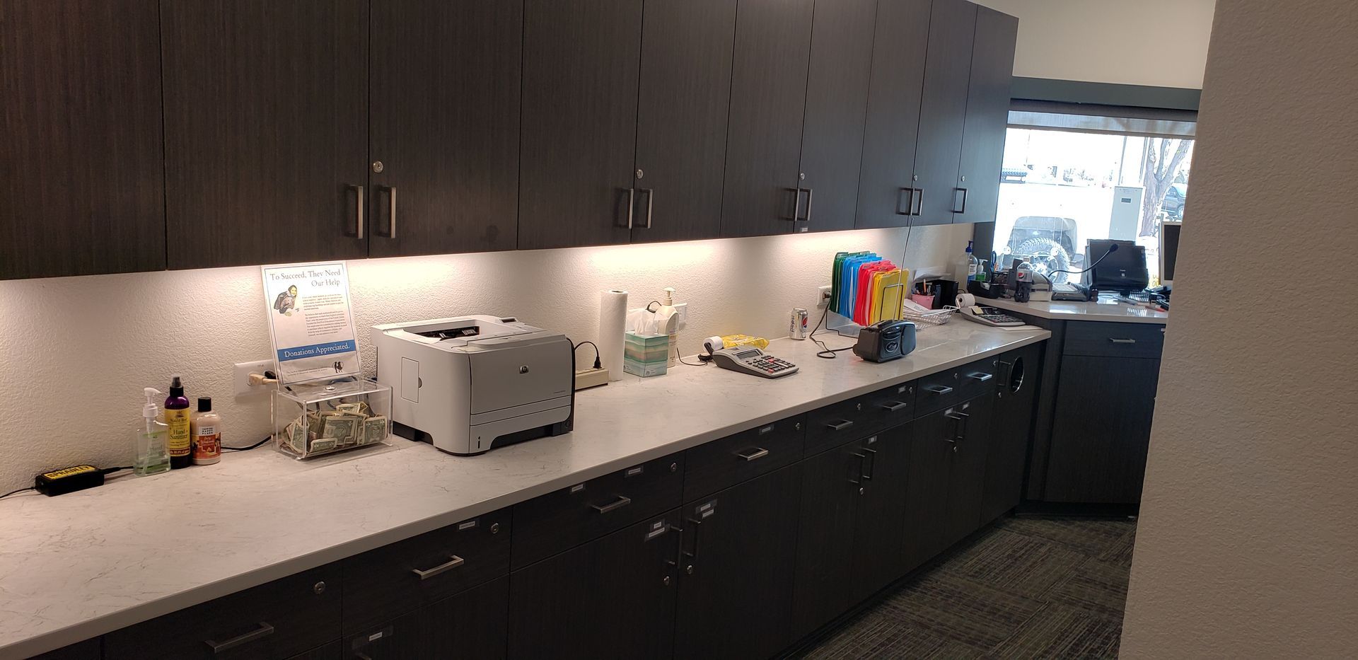 A kitchen with a lot of cabinets and a printer on the counter.
