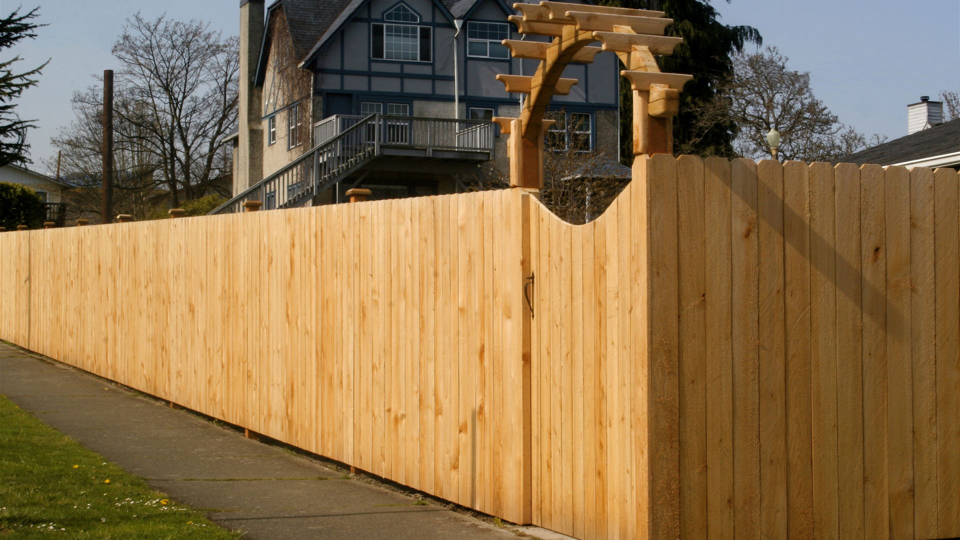 A wooden fence along a sidewalk in front of a house