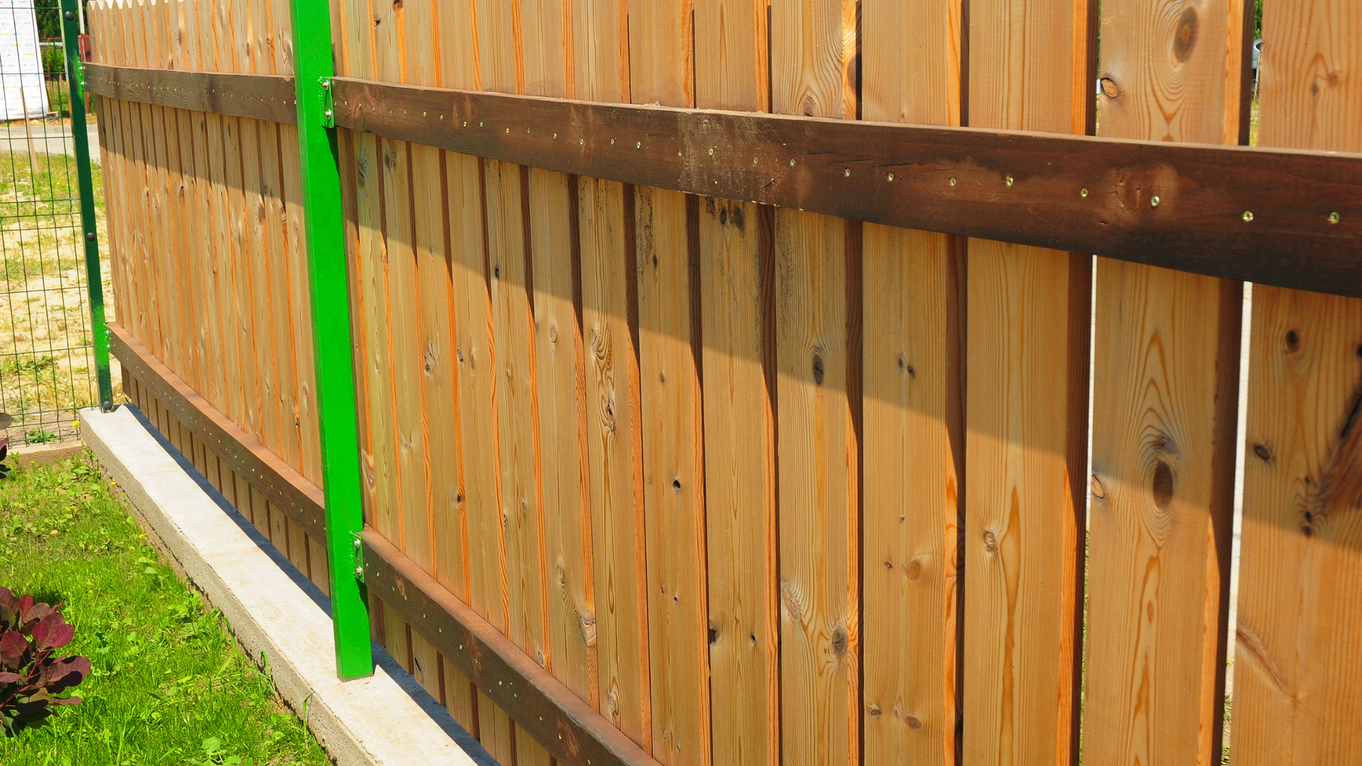 A close up of a wooden fence with a green post.