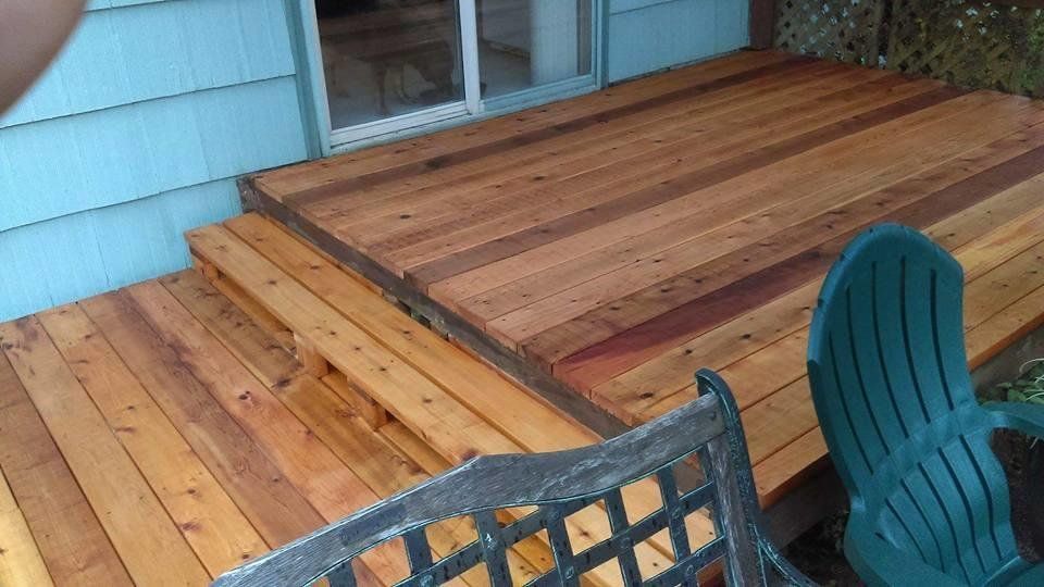 A wooden deck with a bench and chairs on it.