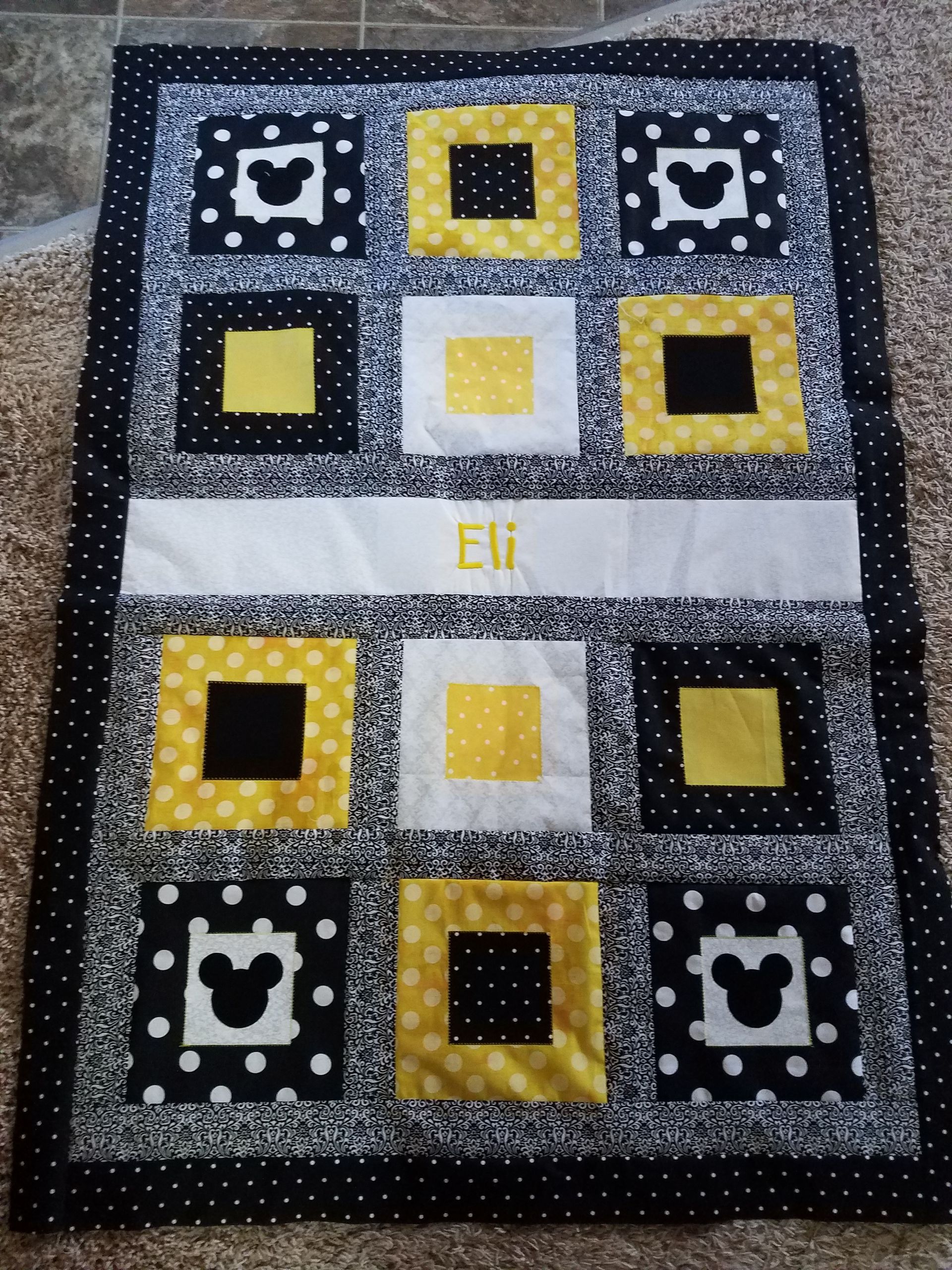 A black and yellow quilt with the name eli on it