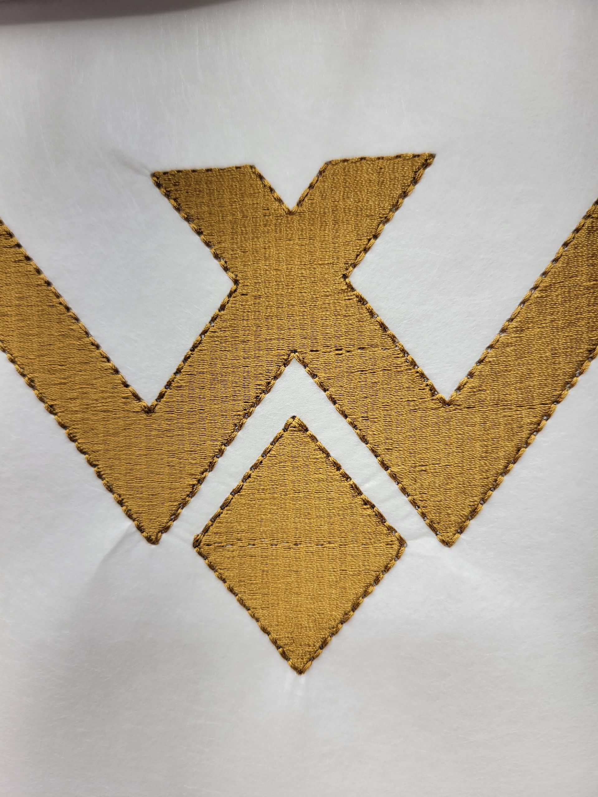A close up of a gold embroidery on a white cloth