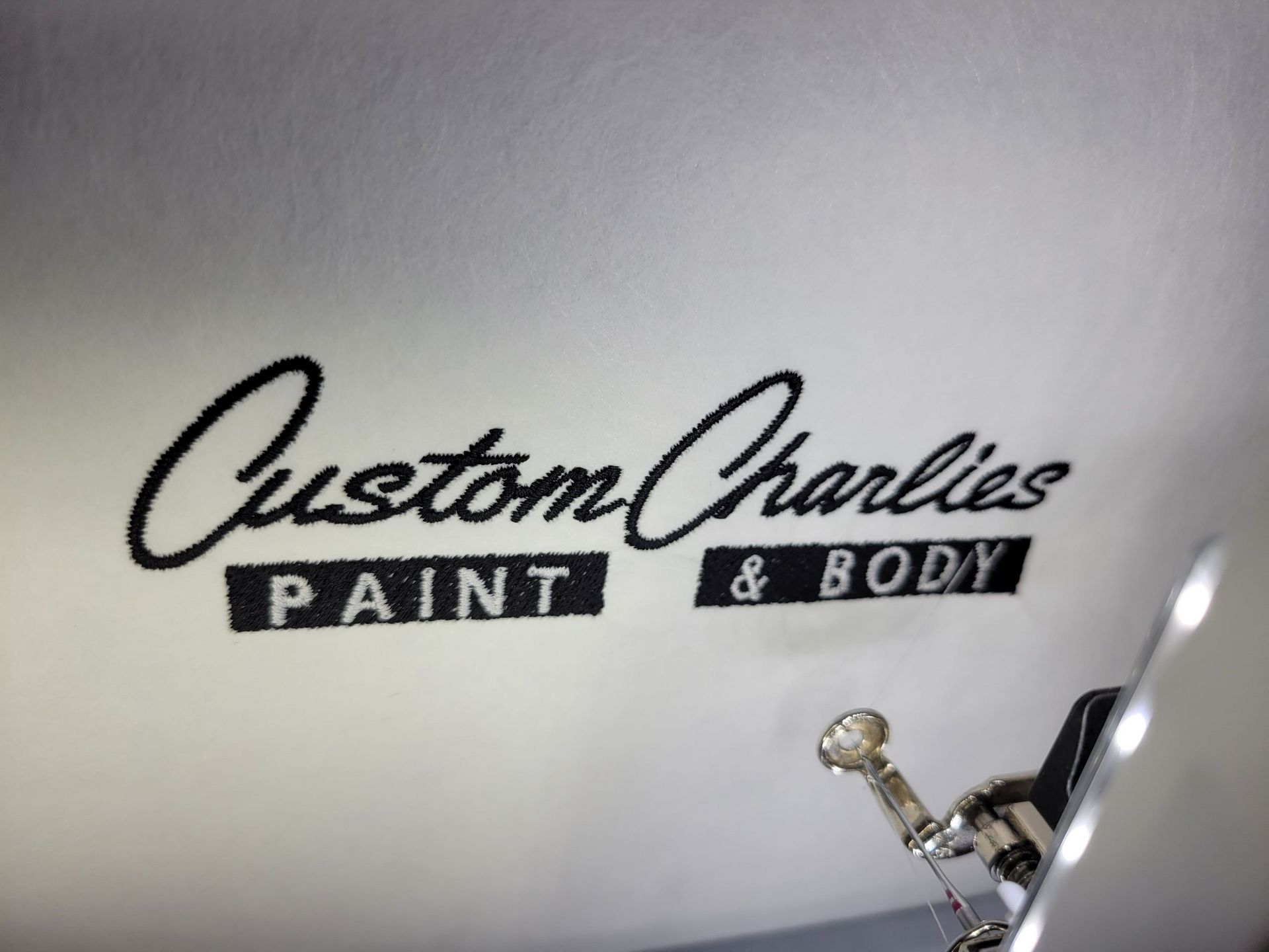 A white wall with the words custom charlies paint and body written on it
