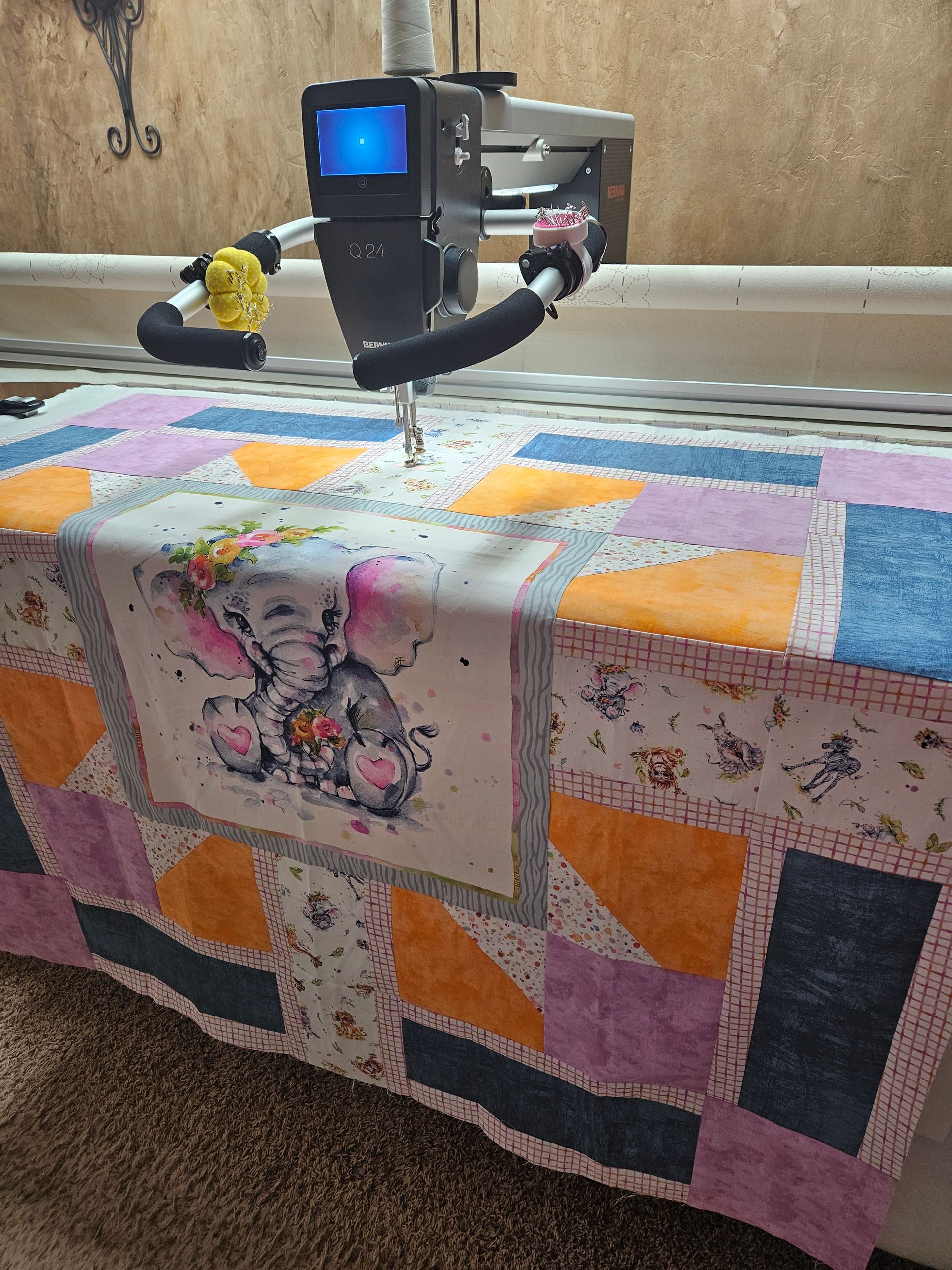A machine is sewing a quilt on a table.