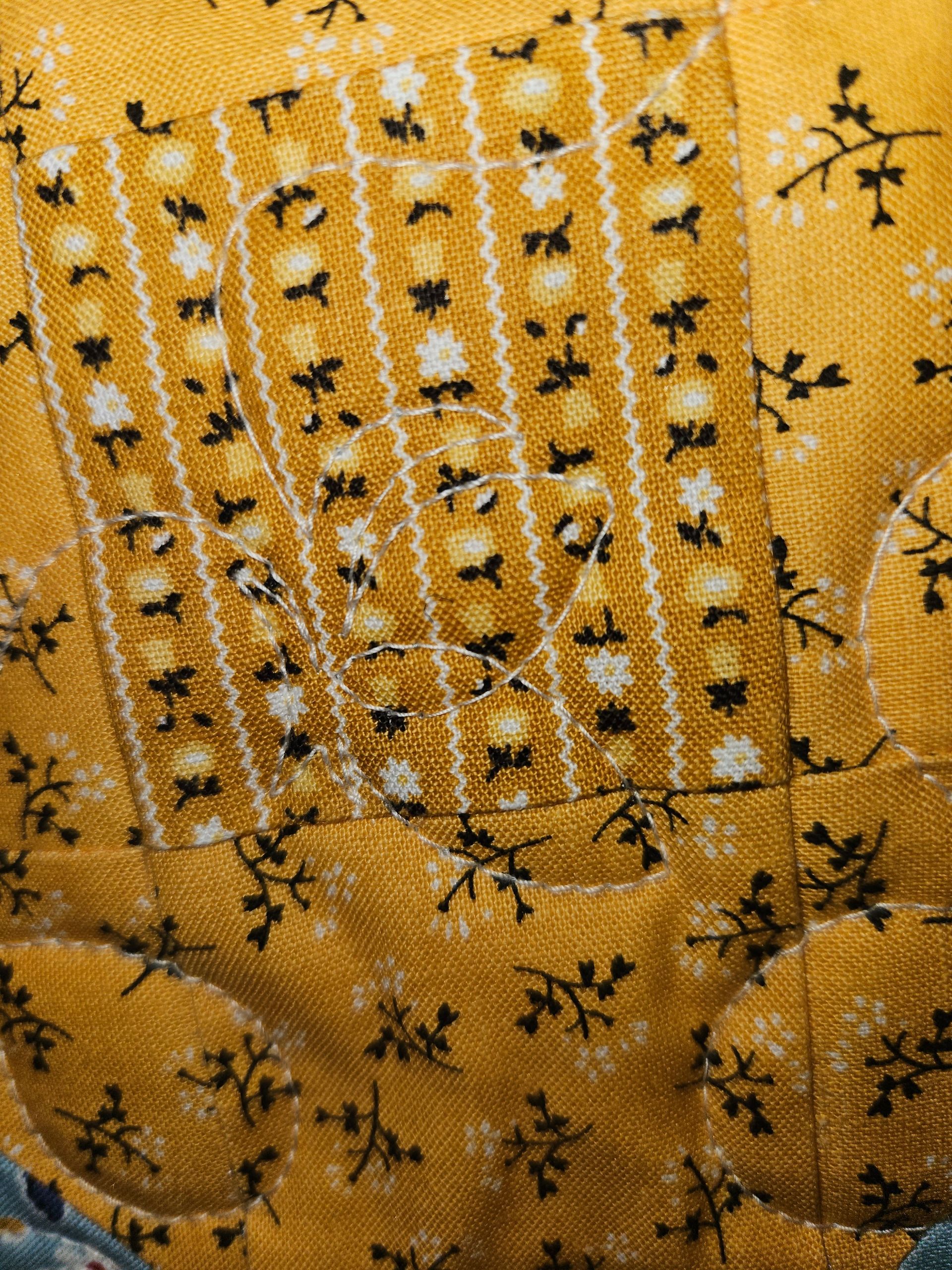 A close up of a yellow quilt with black and white flowers on it.