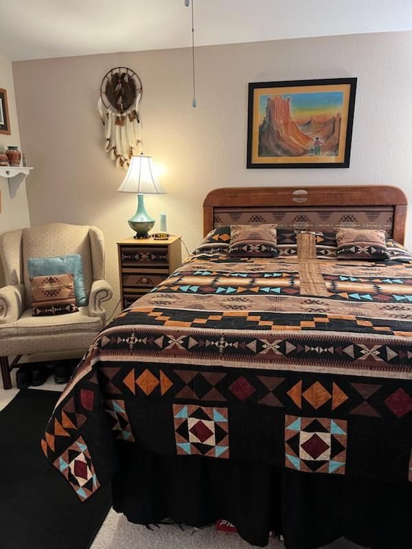 A bedroom with a bed a chair and a lamp