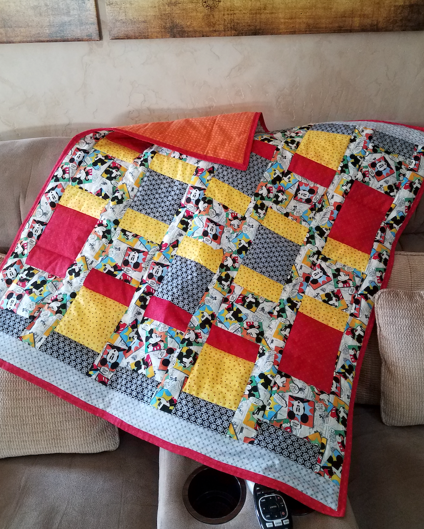 A colorful quilt is sitting on a couch.