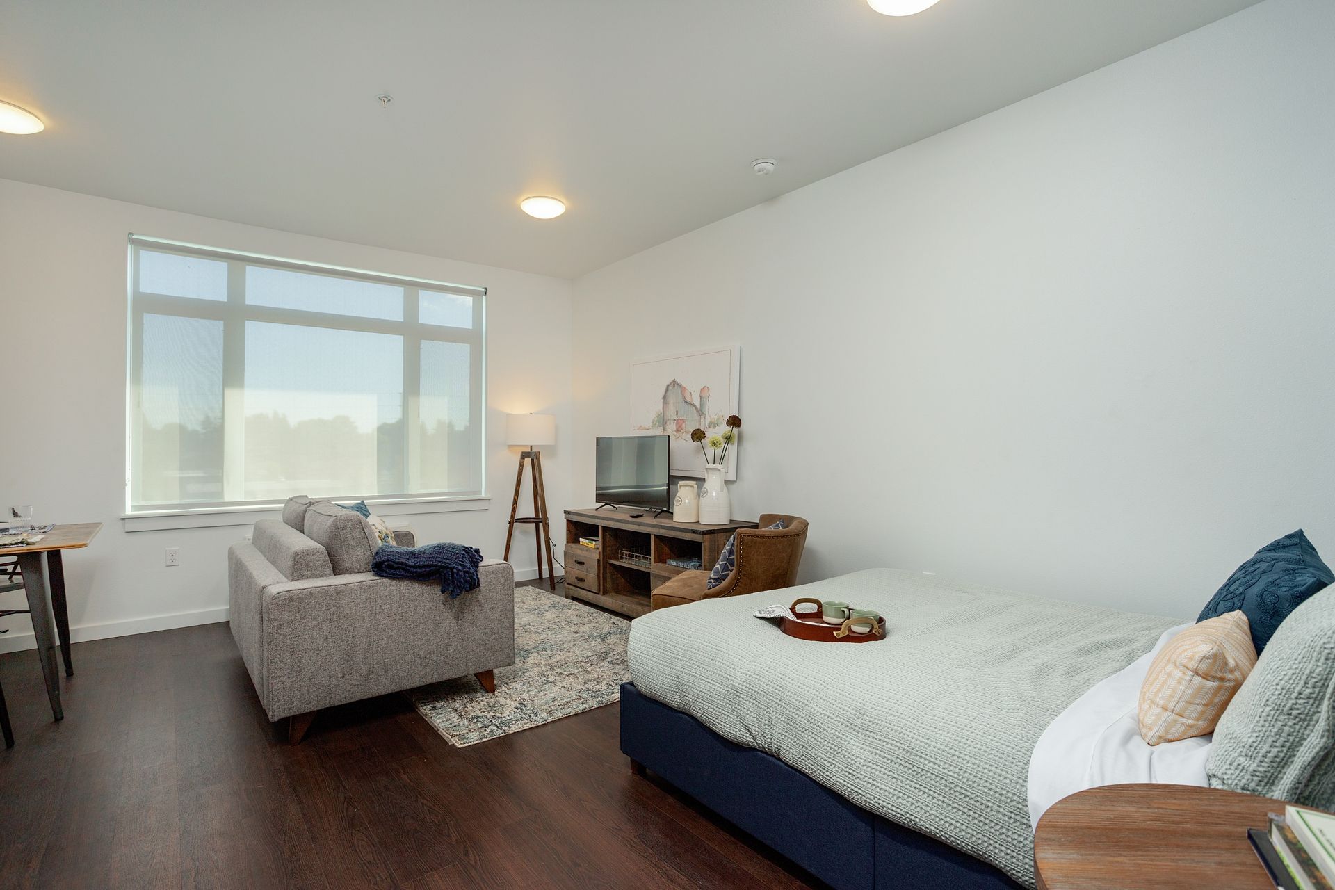 A bedroom with a bed , couch , television and a large window.