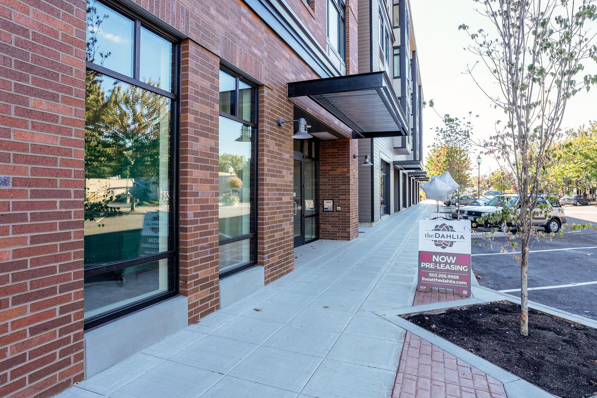 A brick building with a canopy over the entrance and a parking lot in front of it.