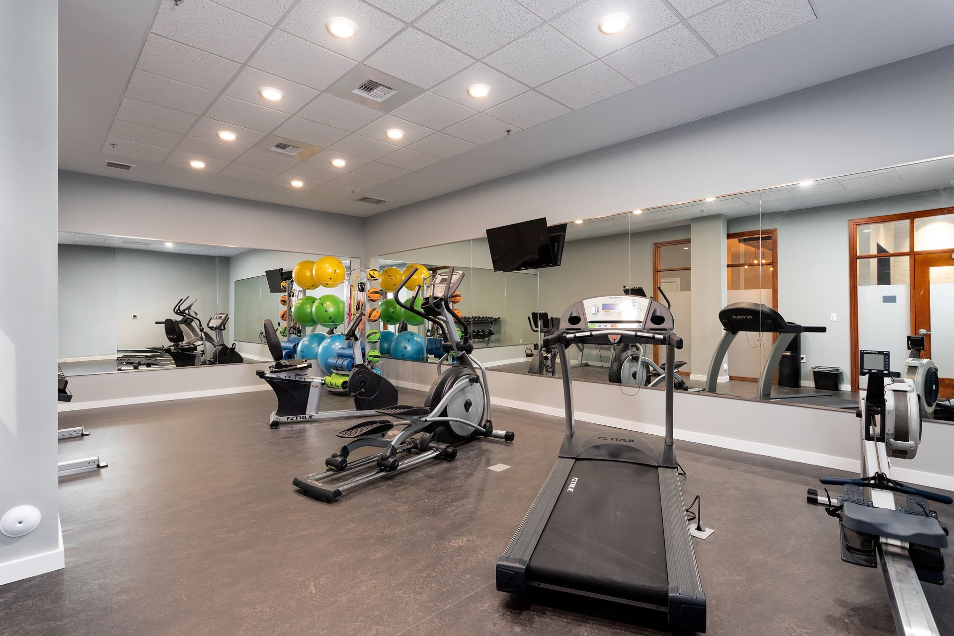A gym with a treadmill , exercise bike , elliptical and other exercise equipment.
