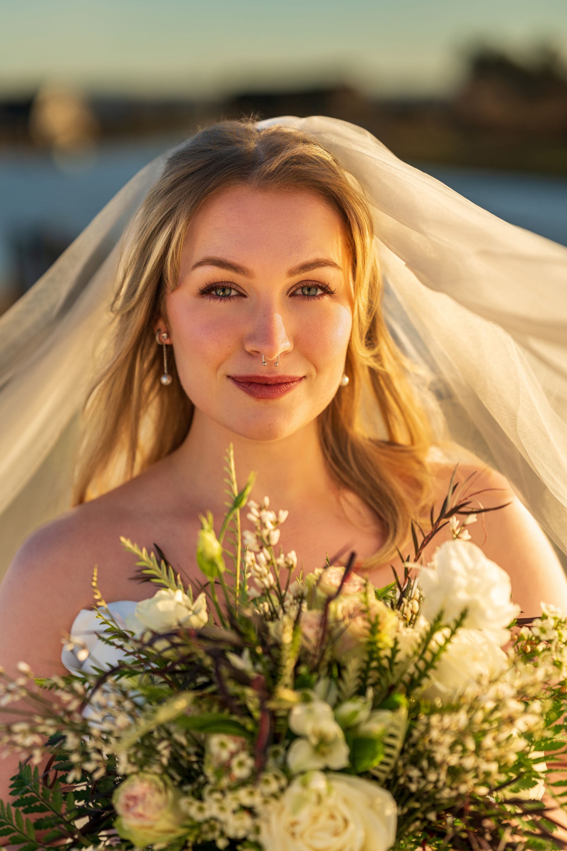 Woman in wedding dress stands near large window in a wood-paneled room.