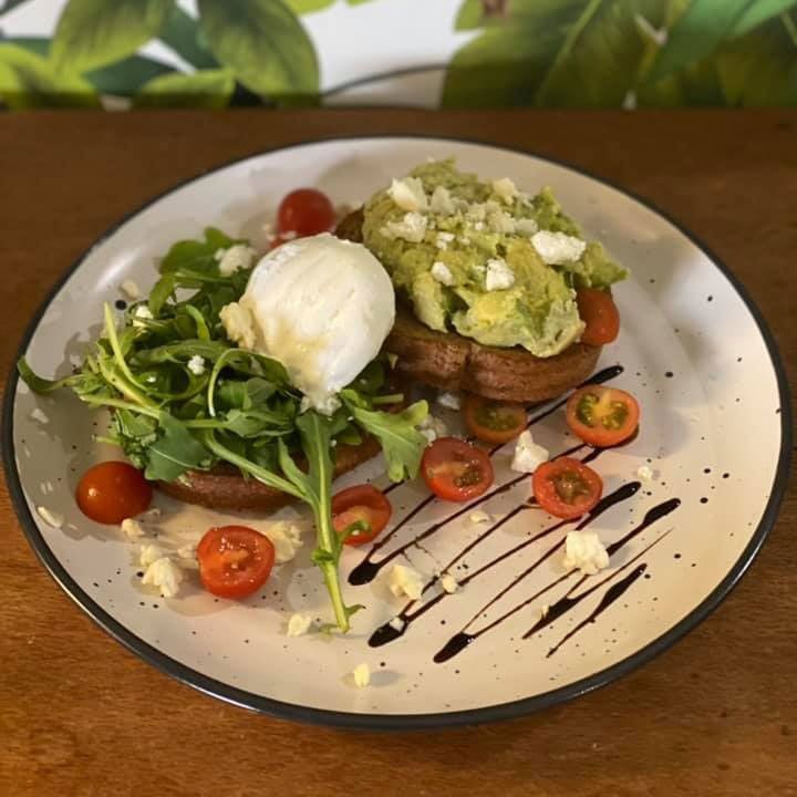 A Plate of Food With Avocado, Tomatoes And a Poached Egg on a Table — Memories Cafe At Yorkeys Knob
