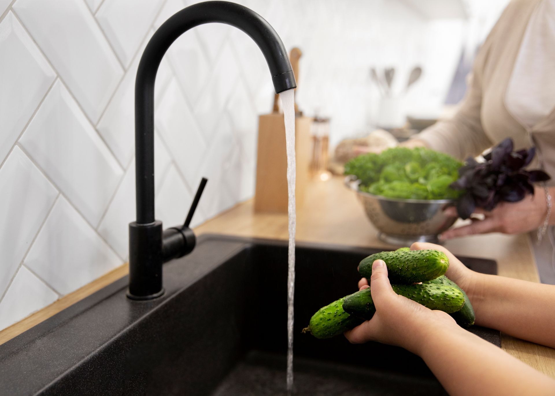 a person is washing cucumbers in a kitchen sink .