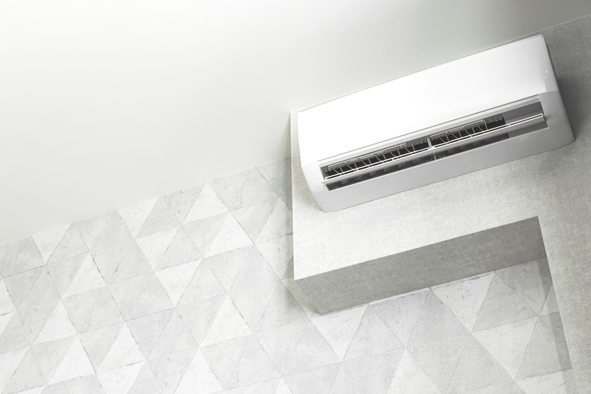 White air conditioner mounted on a white wall with geometric pattern.