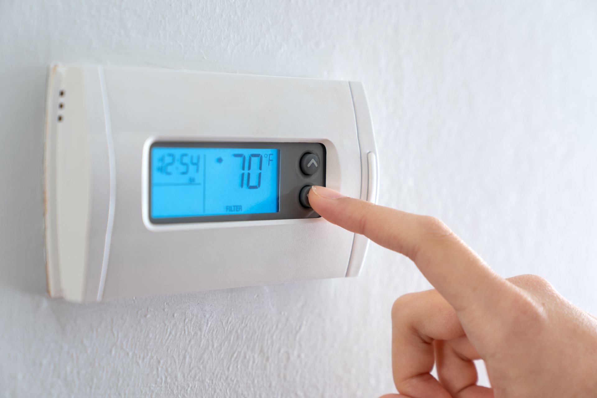 Hand adjusting thermostat; current temperature 70 degrees Fahrenheit, blue display.