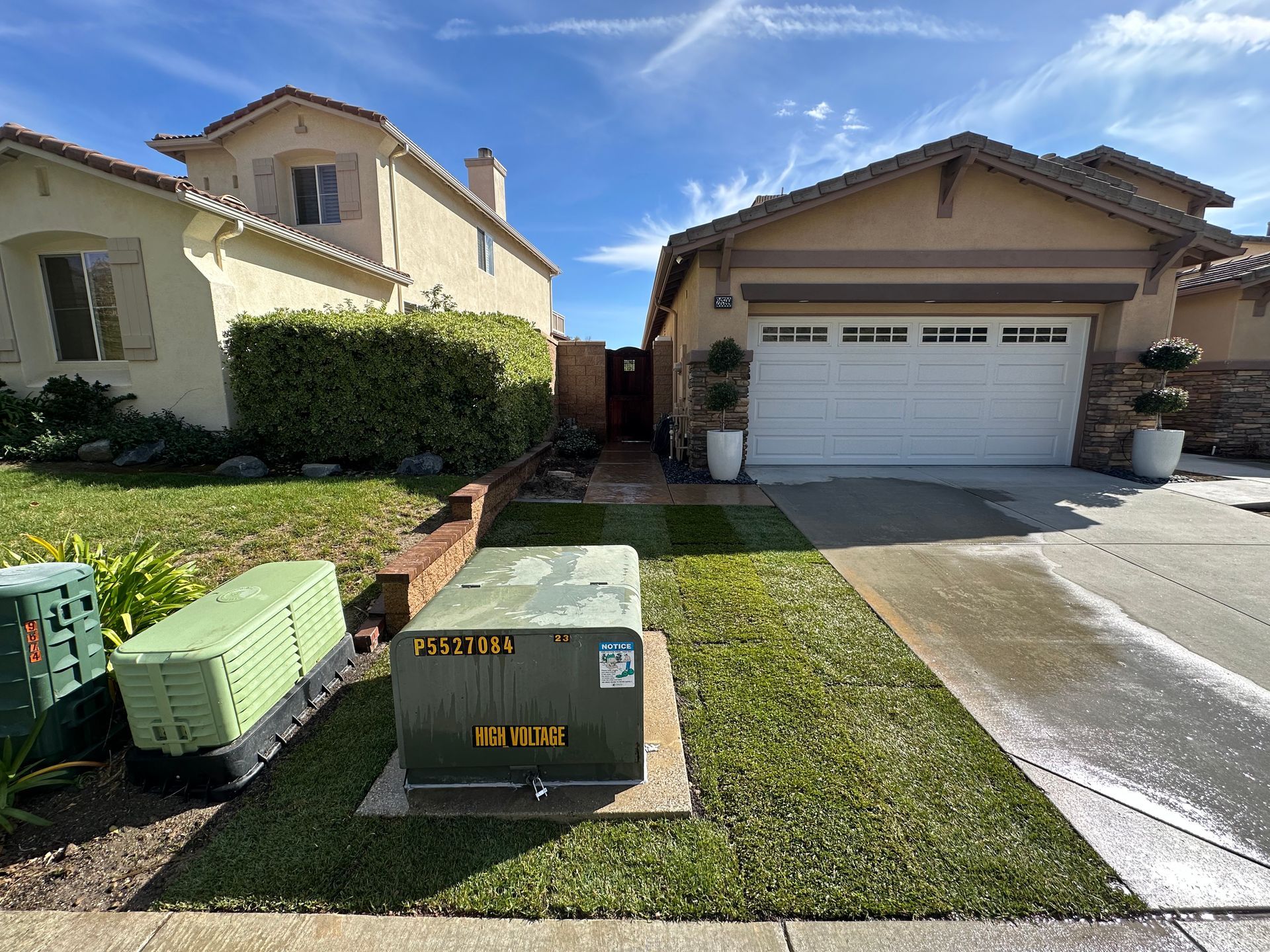 A house with a garage and a generator in front of it.