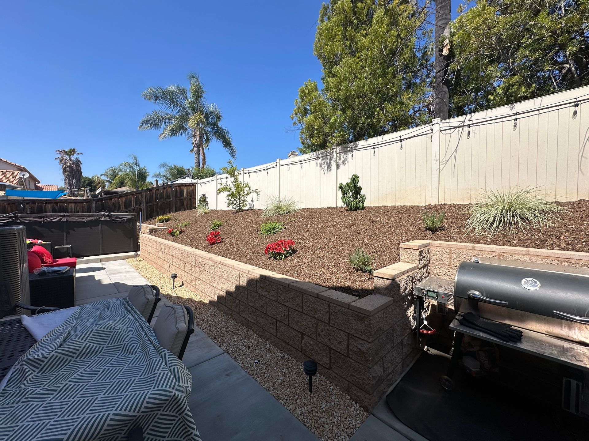 A backyard with a table and chairs and a grill.