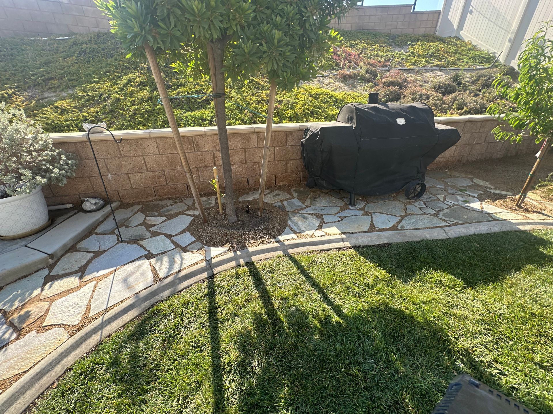 A grill is sitting in the middle of a lush green yard.