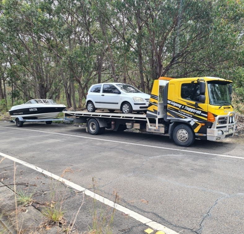 A Tow Truck is Carrying a Car and a Boat on a Trailer — Wyong and Tuggerah Towing Service in Gosford, NSW