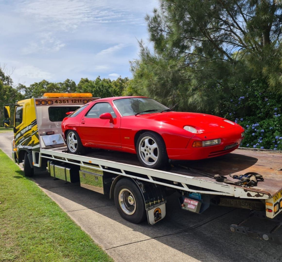 A Red Car is Sitting on Top of a Tow Truck — Wyong and Tuggerah Towing Service in Tuggerah, NSW