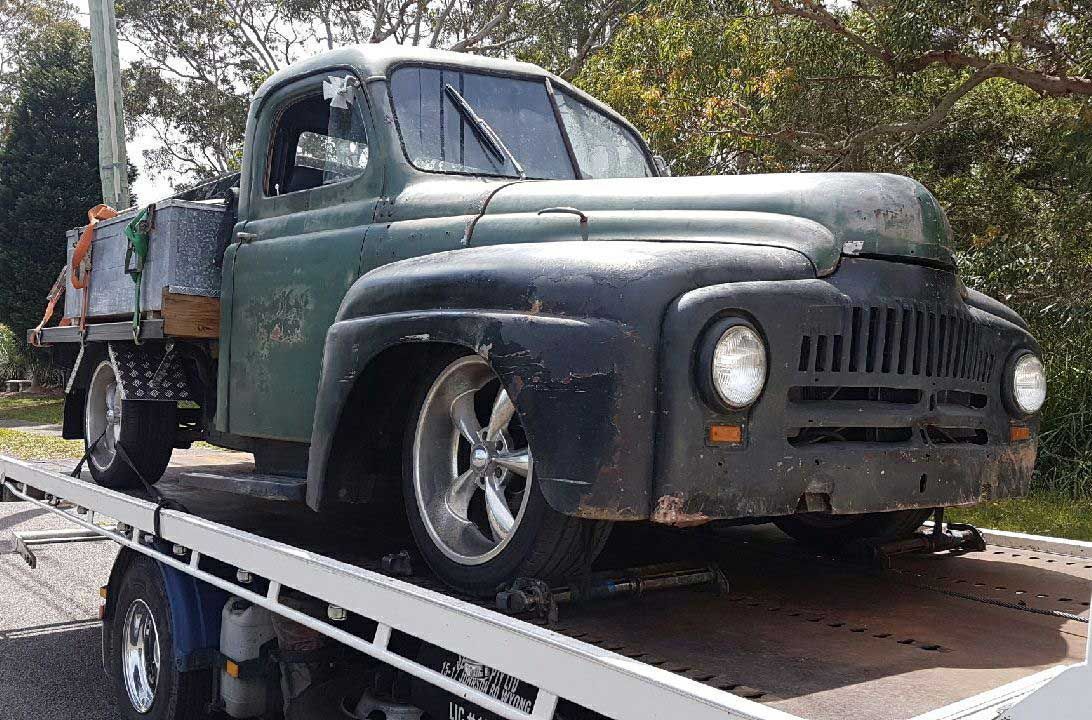An Old Green Truck is Sitting on Top of a Tow Truck — Wyong and Tuggerah Towing Service in Bateau Bay, NSW