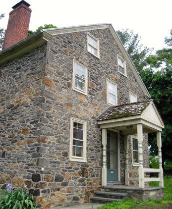 A stone house with a porch and a brick chimney