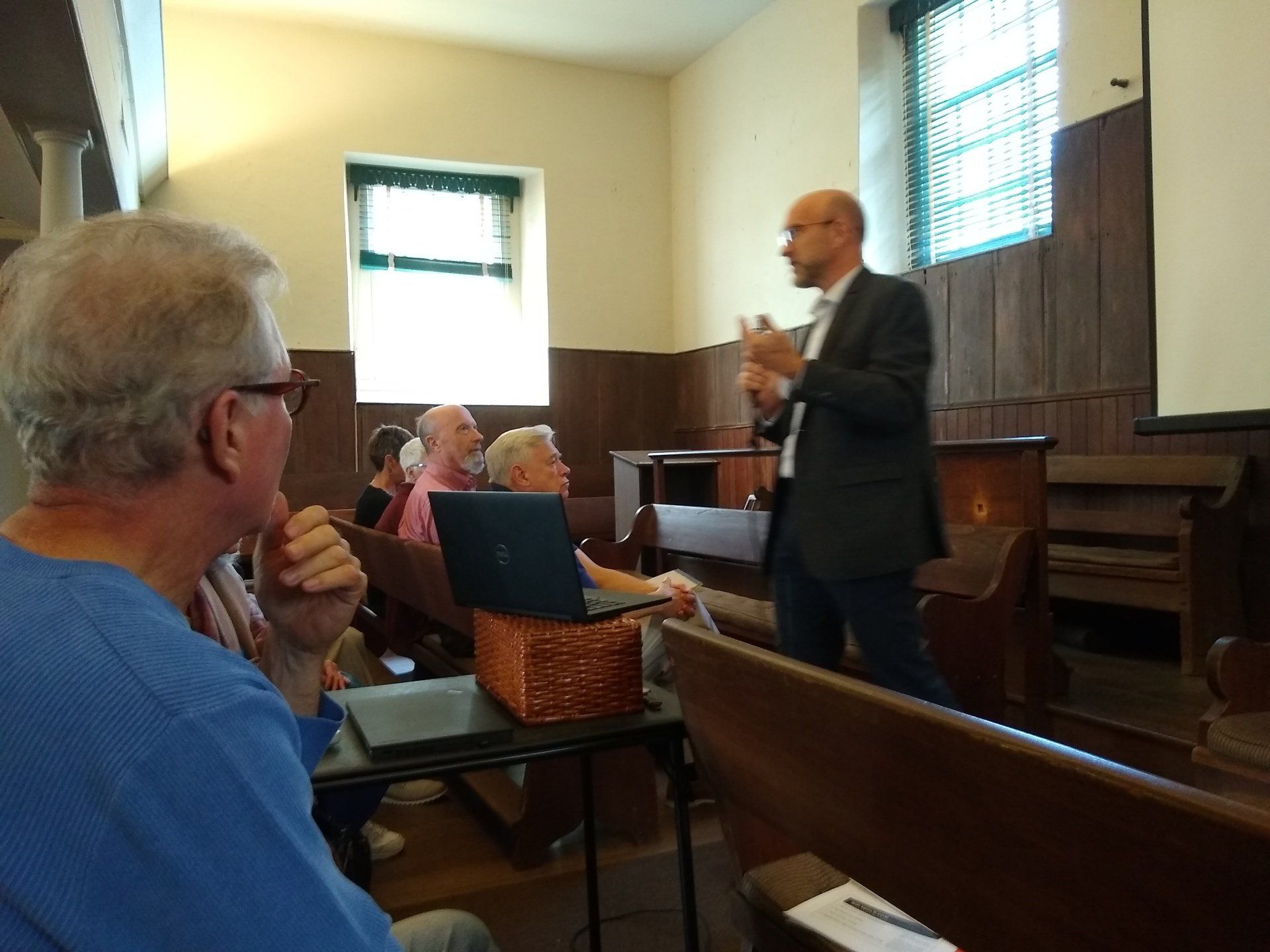 A man in a suit is giving a presentation to a group of people in a church.