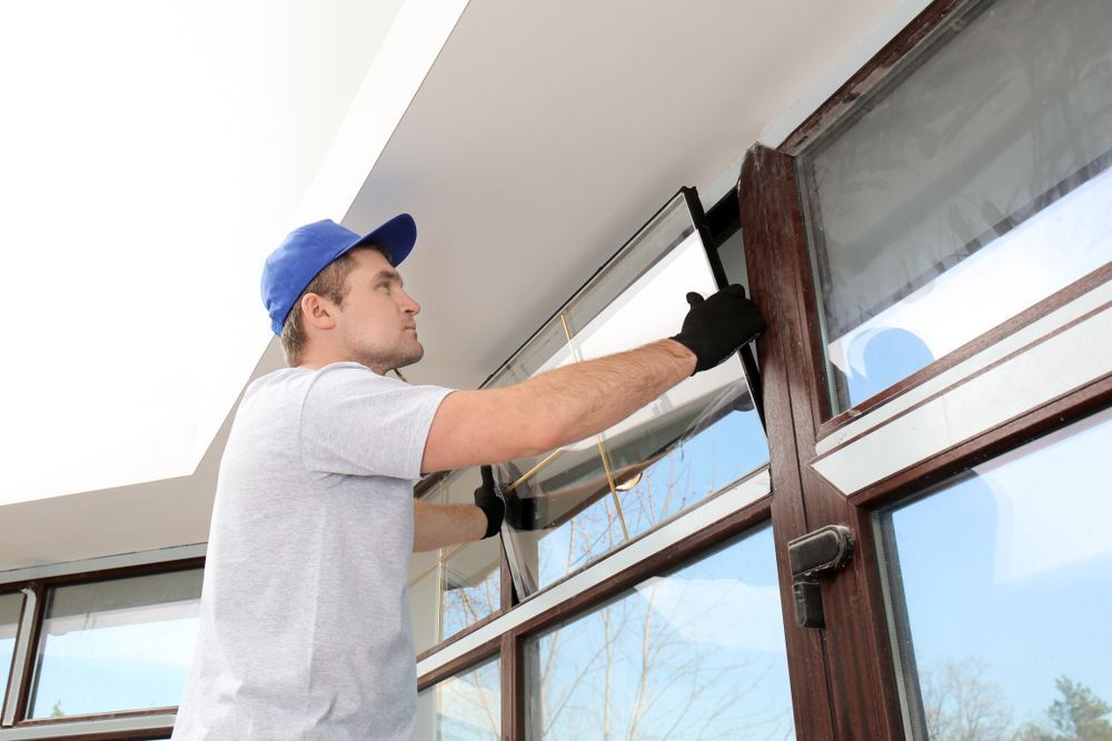 A Professional in a Blue Cap and Work Gloves Installs a Window — Sams Glass Solutions in Proserpine, QLD