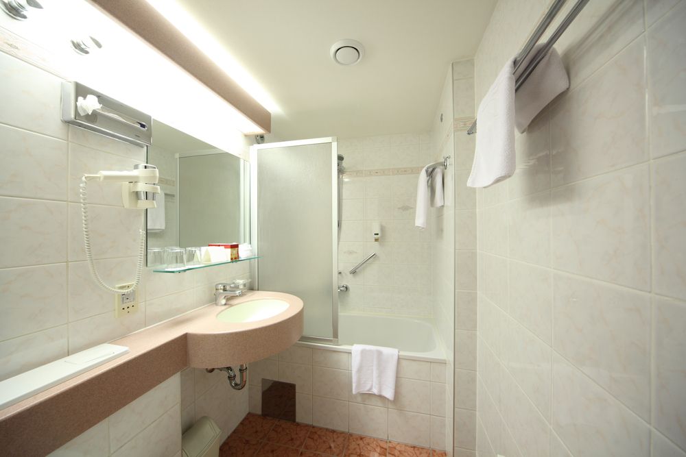 Bathroom With a Sink, Mirror, Bathtub, and Shower Screen — Sams Glass Solutions in Proserpine, QLD