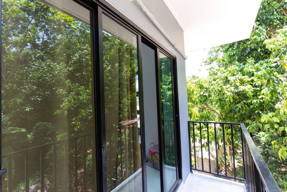 Balcony With Sliding Glass Doors, Black Railing, and Lush Green Trees Visible — Sams Glass Solutions in Proserpine, QLD