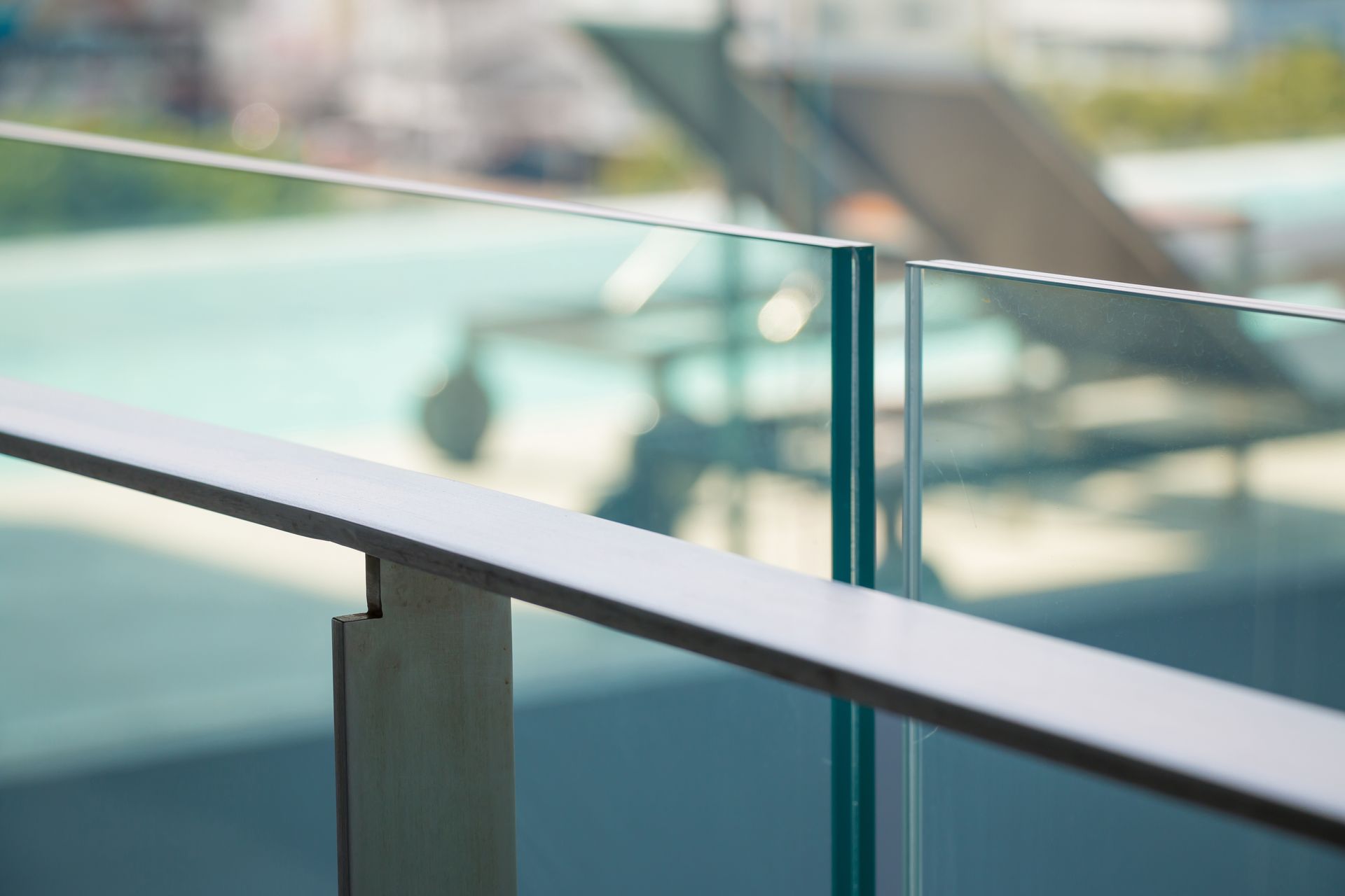Close-up of a Modern Glass and Metal Railing With Blurred Outdoor Background — Sams Glass Solutions in Proserpine, QLD