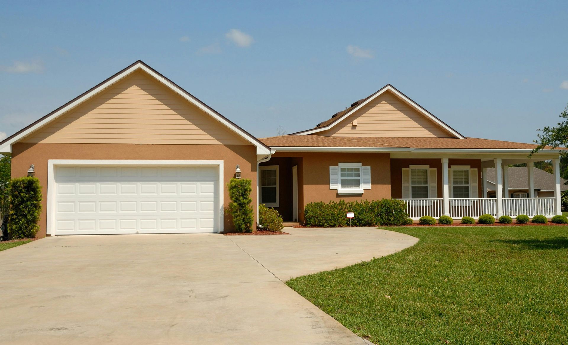 house with white garage, concrete driveway and well-trimmed lawn
