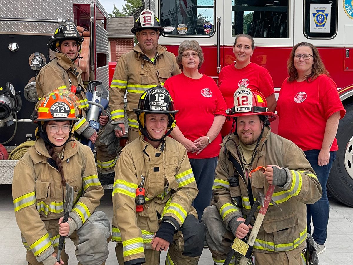 A row Akron firefighters' uniforms and helmets hanging on a rack.