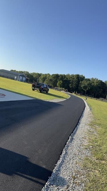 A truck is driving down a curvy road next to a grassy hill.