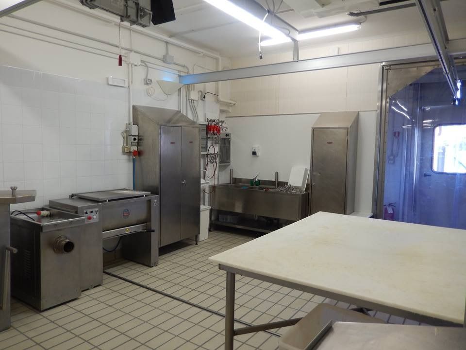 Cucina commerciale in acciaio inox con elettrodomestici e un ampio tavolo da lavoro.