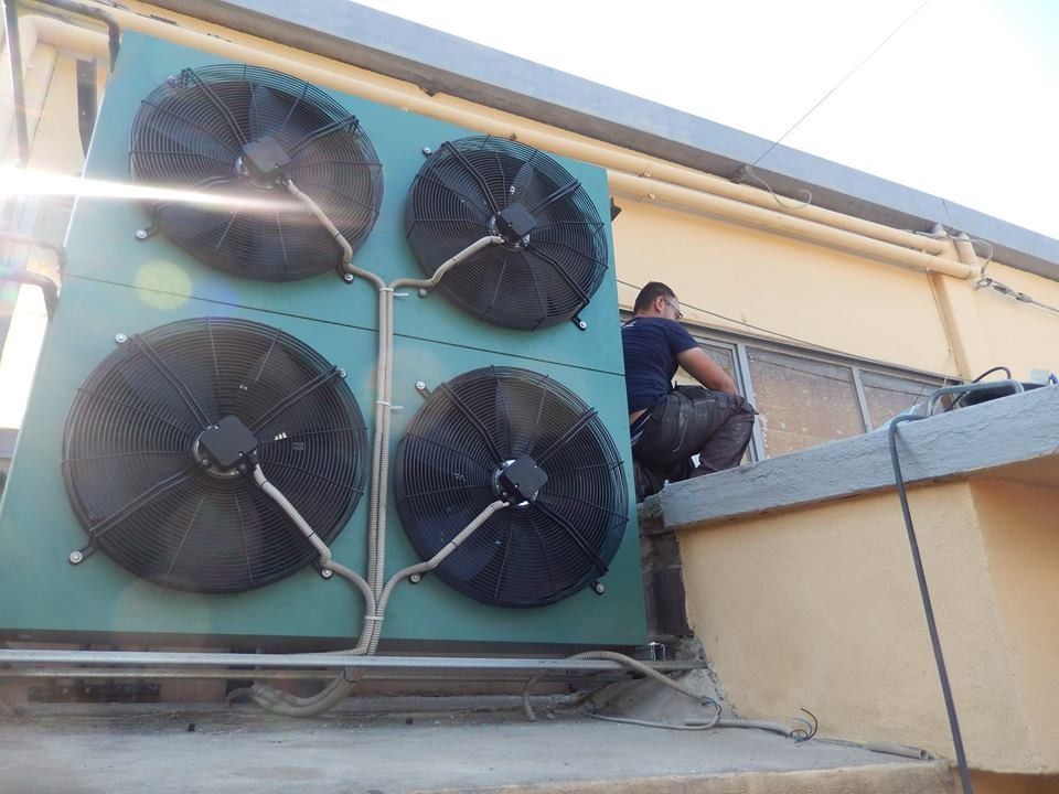 Uomo al lavoro su un condizionatore d'aria sul tetto dotato di quattro ventole.