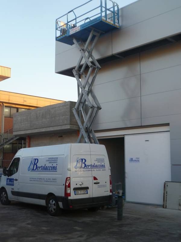 Furgone bianco parcheggiato vicino a un edificio con una piattaforma elevatrice che arriva fino al muro