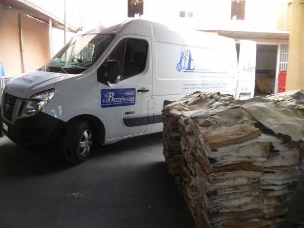 Furgone bianco con il logo aziendale parcheggiato vicino a pile di pelli.