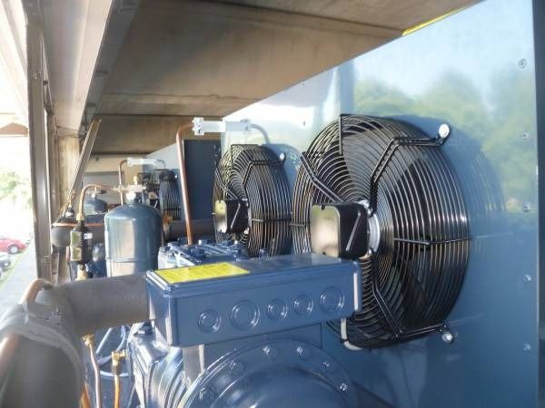 Unità di refrigerazione in metallo con tre ventole nere, scatola elettrica blu e tubi argentati, all'esterno.