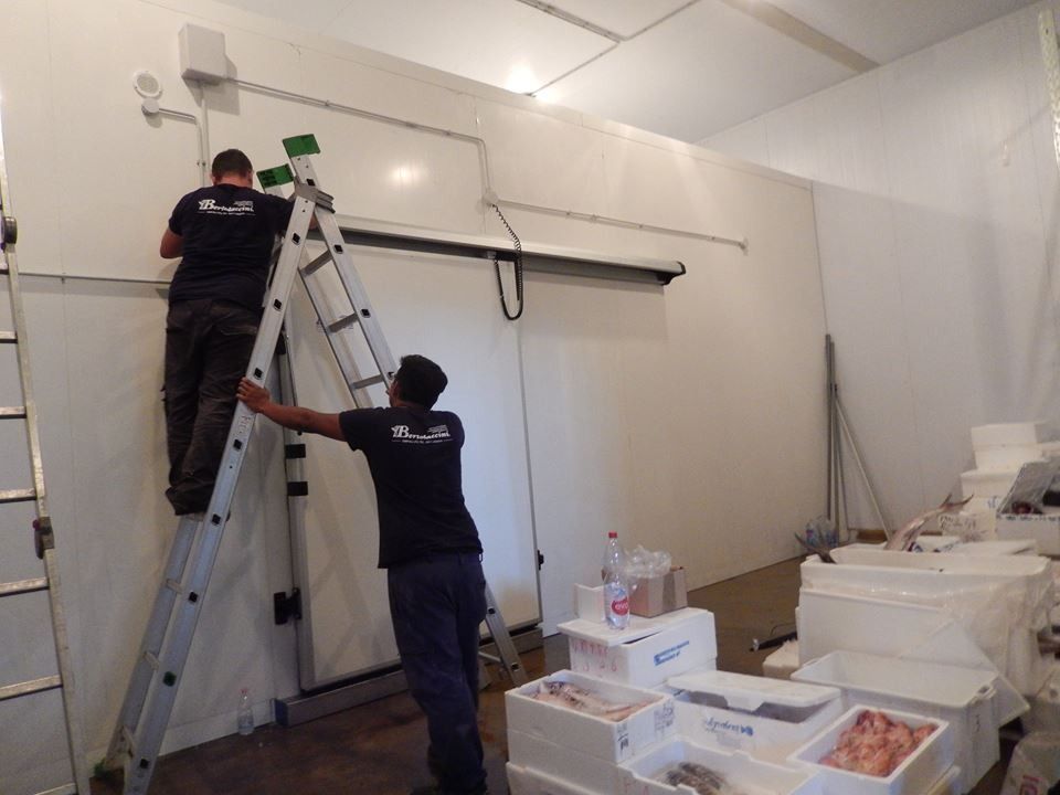 Due operai installano attrezzature all'interno di un congelatore commerciale 