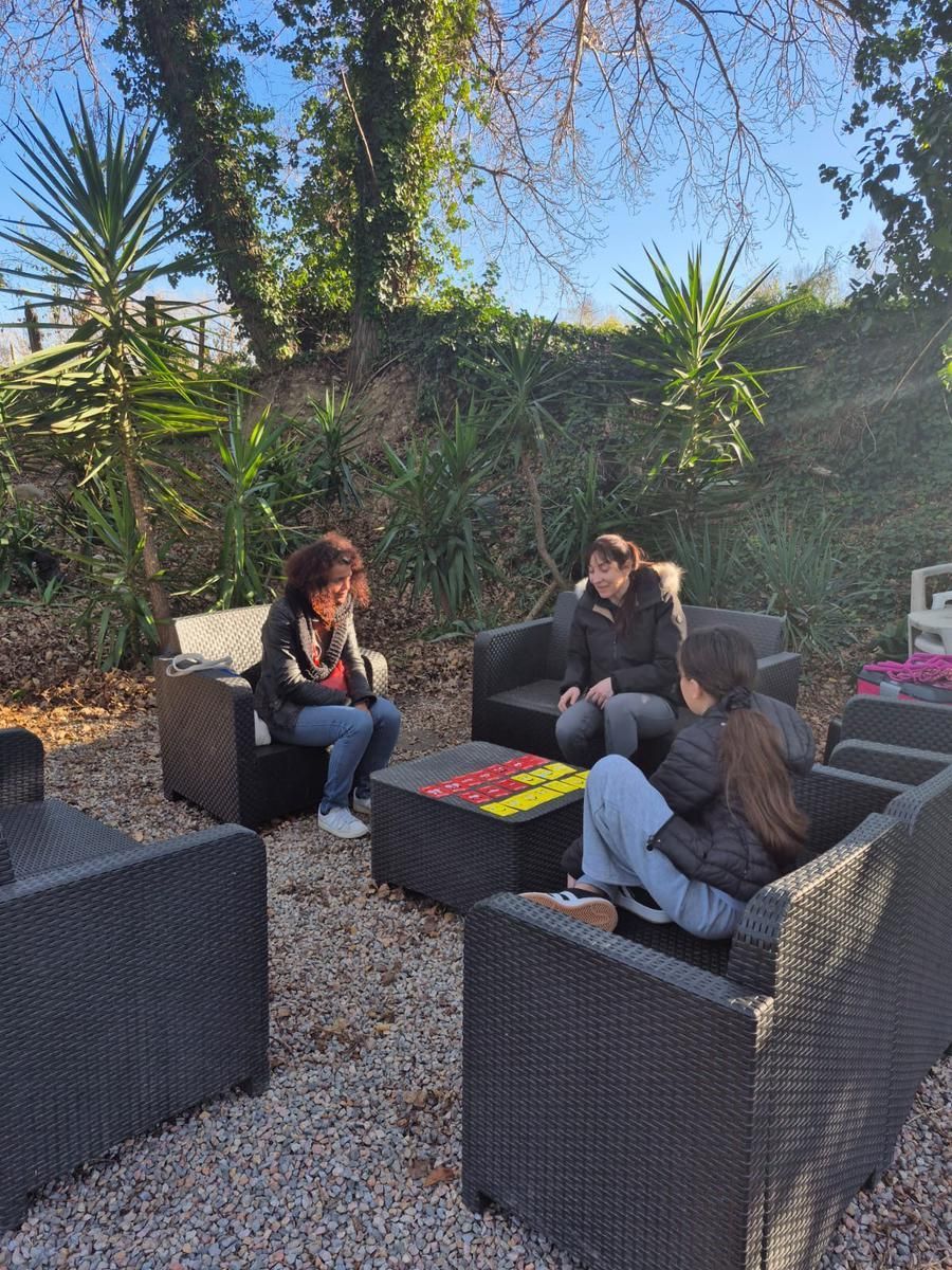 Trois personnes jouent à un jeu autour d'une table dans un espace extérieur.
