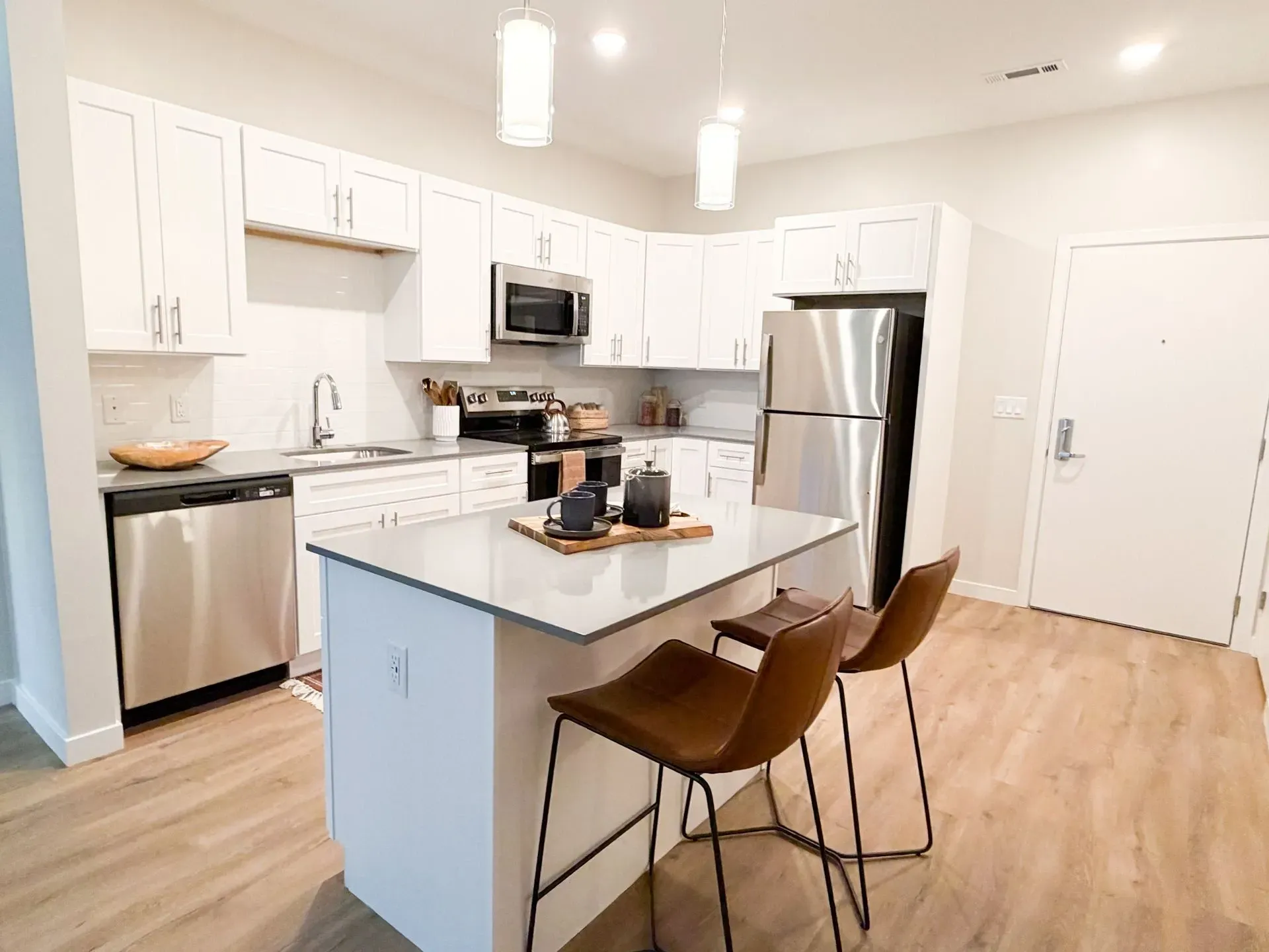 Modern white kitchen in an apartment with stainless steel appliances and an island.
