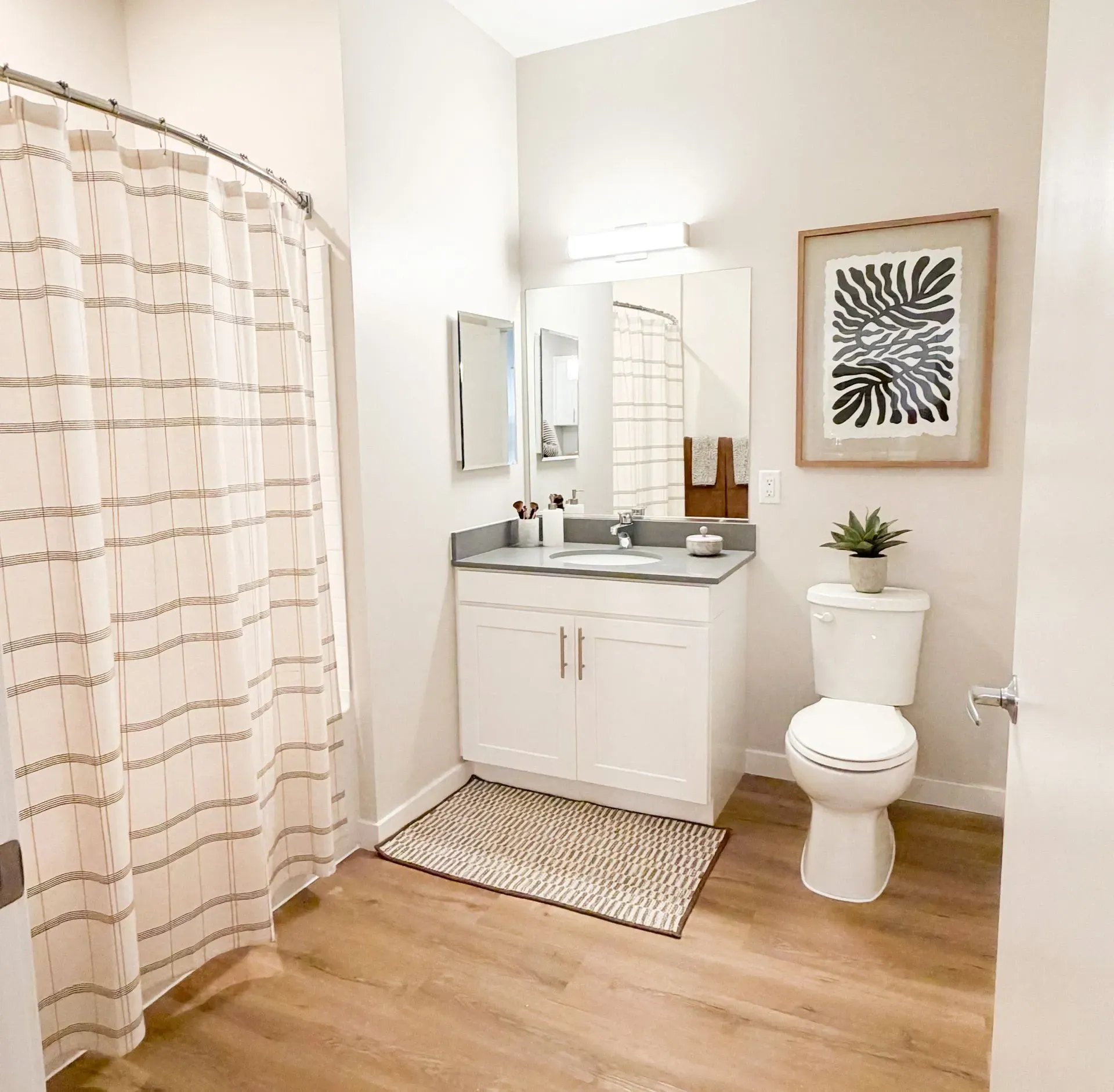Bathroom with vanity, mirror, toilet, and striped shower curtain in a modern apartment.