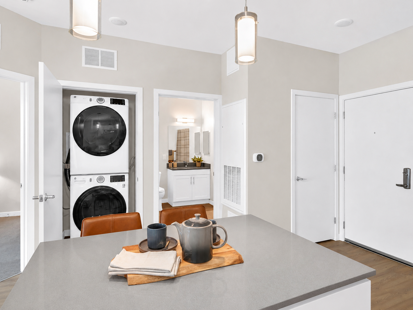 Dining table with a teapot and two mugs on a wooden tray in an apartment kitchen.