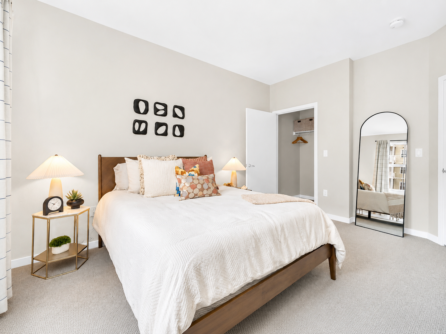 Bedroom with a wooden bed, two nightstands, lamps, and an abstract painting on the wall.